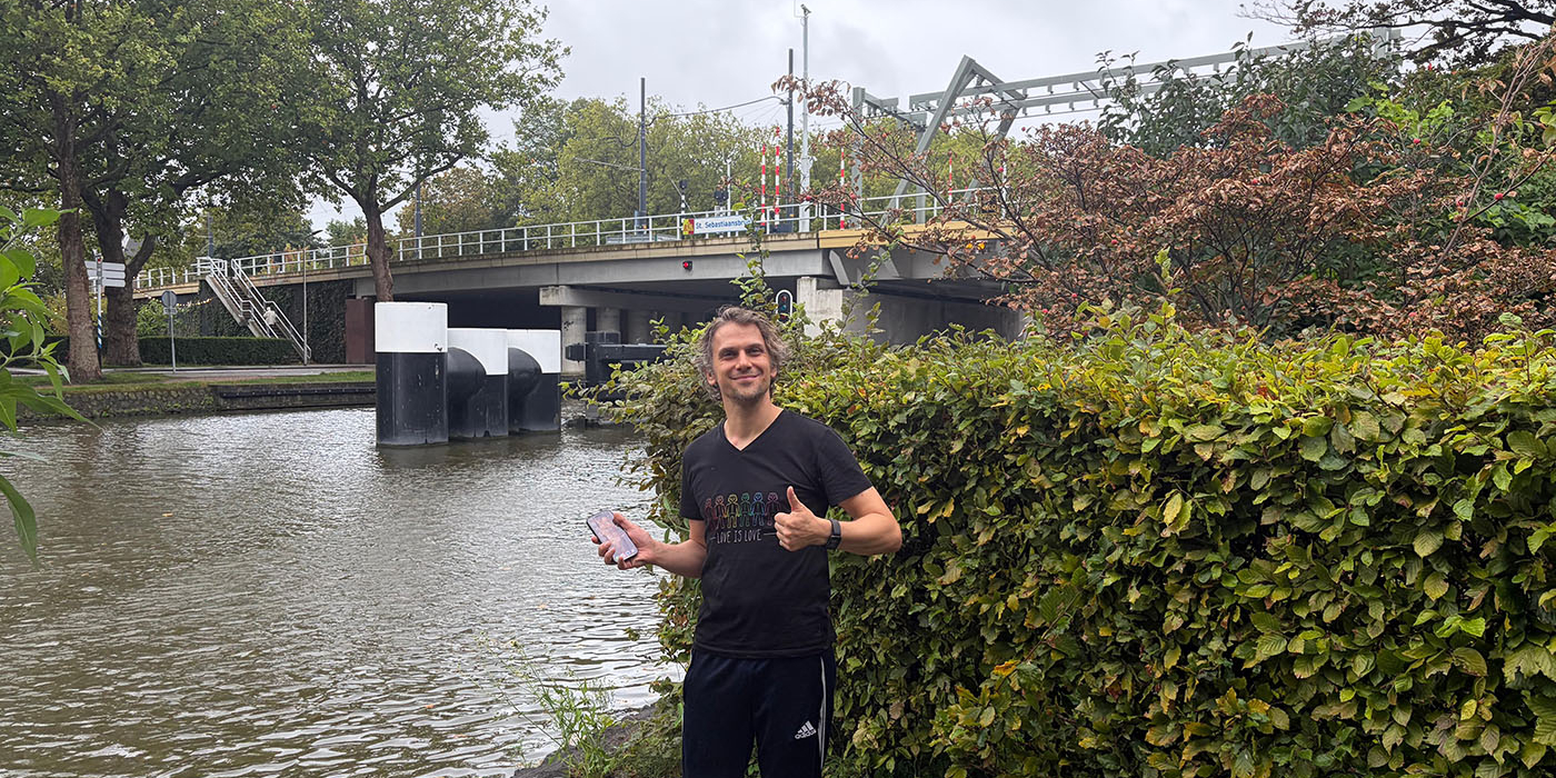 Eigenaar met zijn teruggevonden telefoon aan de gracht in Delft
