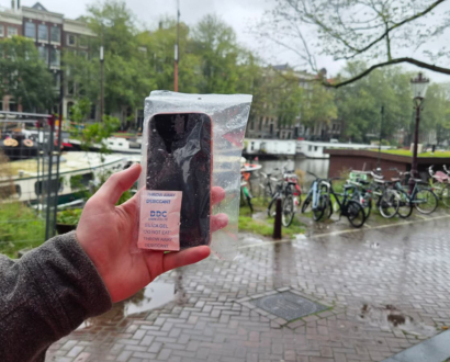 Hand met de teruggevonden telefoon aan de gracht